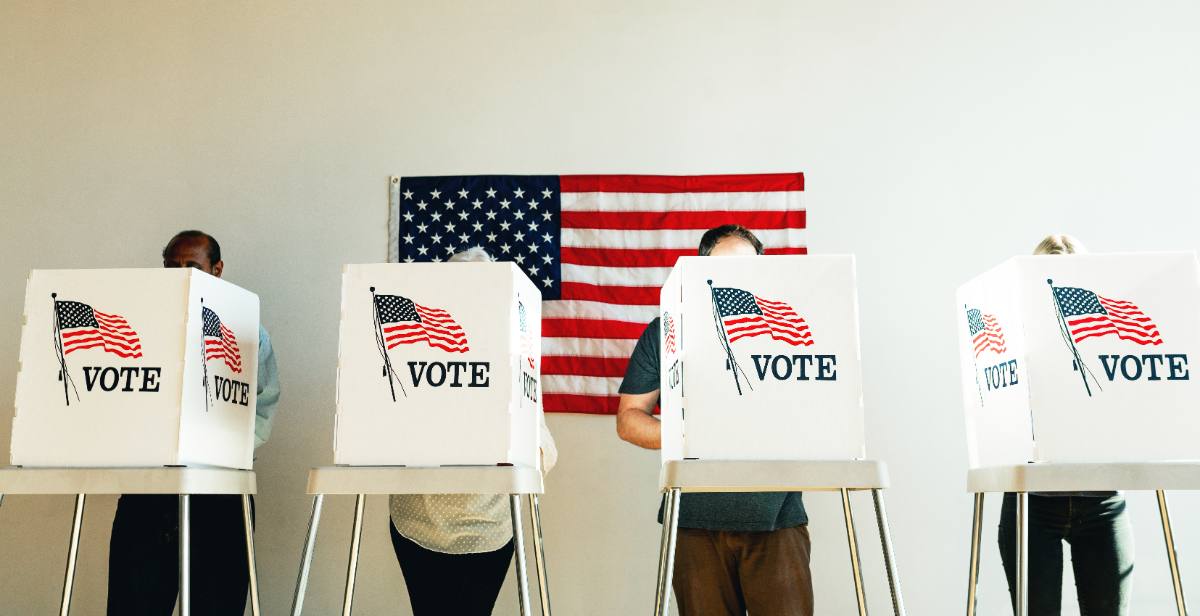 Voters at booths, viewed from behind, no faces visible